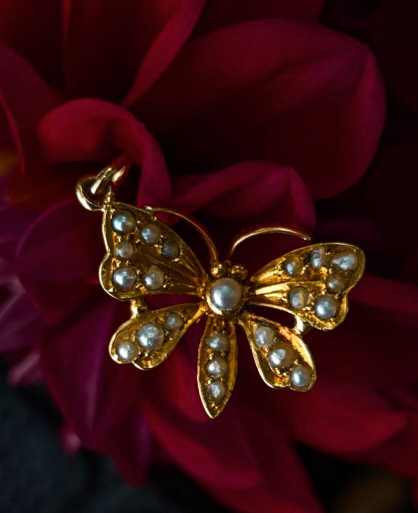 Seed Pearl & Gold Butterfly Charm on a flower